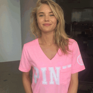 Ad gif. Smiling woman wearing a Victoria's Secret Pink shirt gives a double thumbs-up, playfully bobbing her shoulders side to side.