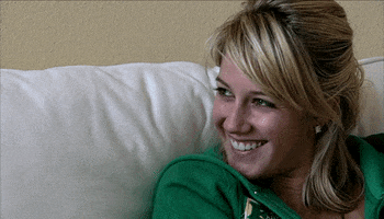 Reality TV gif. Heidi Montag from The Hills is curled up on a couch and she's grinning.