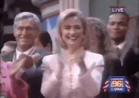 Political gif. A young Hillary Clinton stands in a crowd of people. She looks us and claps along with everyone while a big smile on her face.