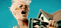 Music Video gif. Pink in the So What music video looks down at someone with big goggles on her face and messy hair. She holds a chainsaw up and then tilts her head back, shaking it around as she laughs evilly.