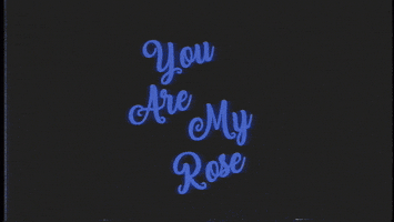 Celebrity gif. Wearing sunglasses and a suit vest, actor Tommy Wiseau emerges beneath the message, “You are my rose,” twirling a rose in his hands, then sniffing it.
