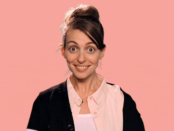 a woman is smiling and making a funny face on a pink background .