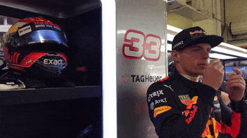 Sports gif. Max Verstappen of Red Bull's Formula One racing team is in his uniform and is preparing for a race, heating up his earbuds in his hands as his helmet sits next to him.
