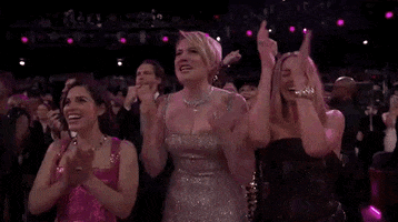 Oscars 2024 GIF. Greta Gerwig, America Ferrera, and Margot Robbie, front row at the Oscars, fangirl out, cheering loudly.
