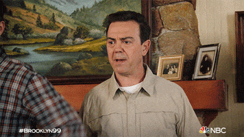TV gif. Joe Lo Truglio as Charles and Andy Samberg as Jake in Brooklyn Nine Nine. They're in a cabin and Charles is upset and about to say something but Jake clamps a hand on his chest and holds him back.