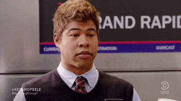 TV gif. Airline employee Jordan Peele from Key and Peele shows he doesn't care by taking a long, deliberate sip of coffee with his pinky out.