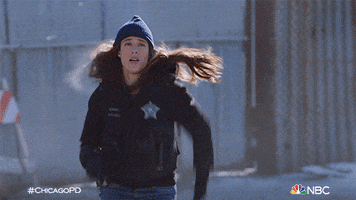 TV gif. Sophia Bush as Erin on Chicago PD wears a police vest and a beanie as she runs towards us. 