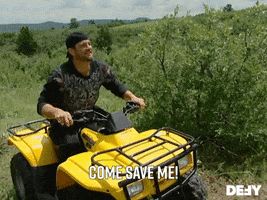 Reality TV gif. In a scene from Dog the Bounty Hunter, we see a large grassy field, where a man in a bandanna stands up on a yellow ATV and shouts: Text, "Come save me!"